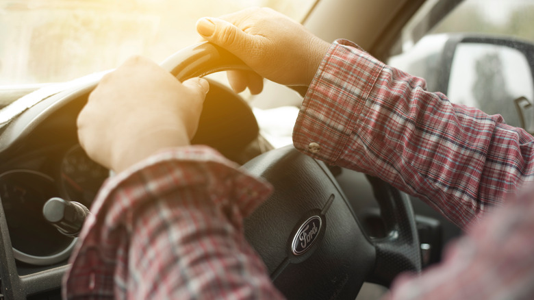 hands holding Ford steering wheel