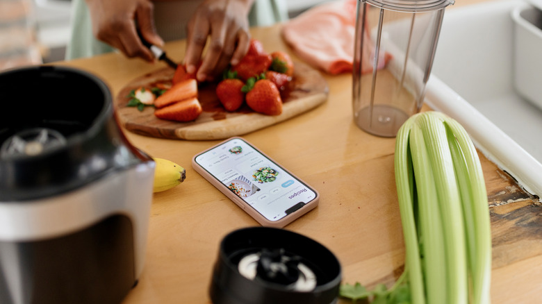 cutting strawberries, recipe on phone