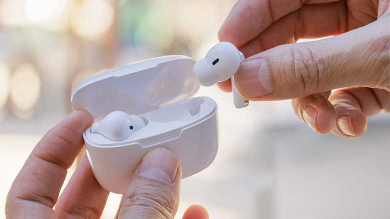 person pulling out white earbuds